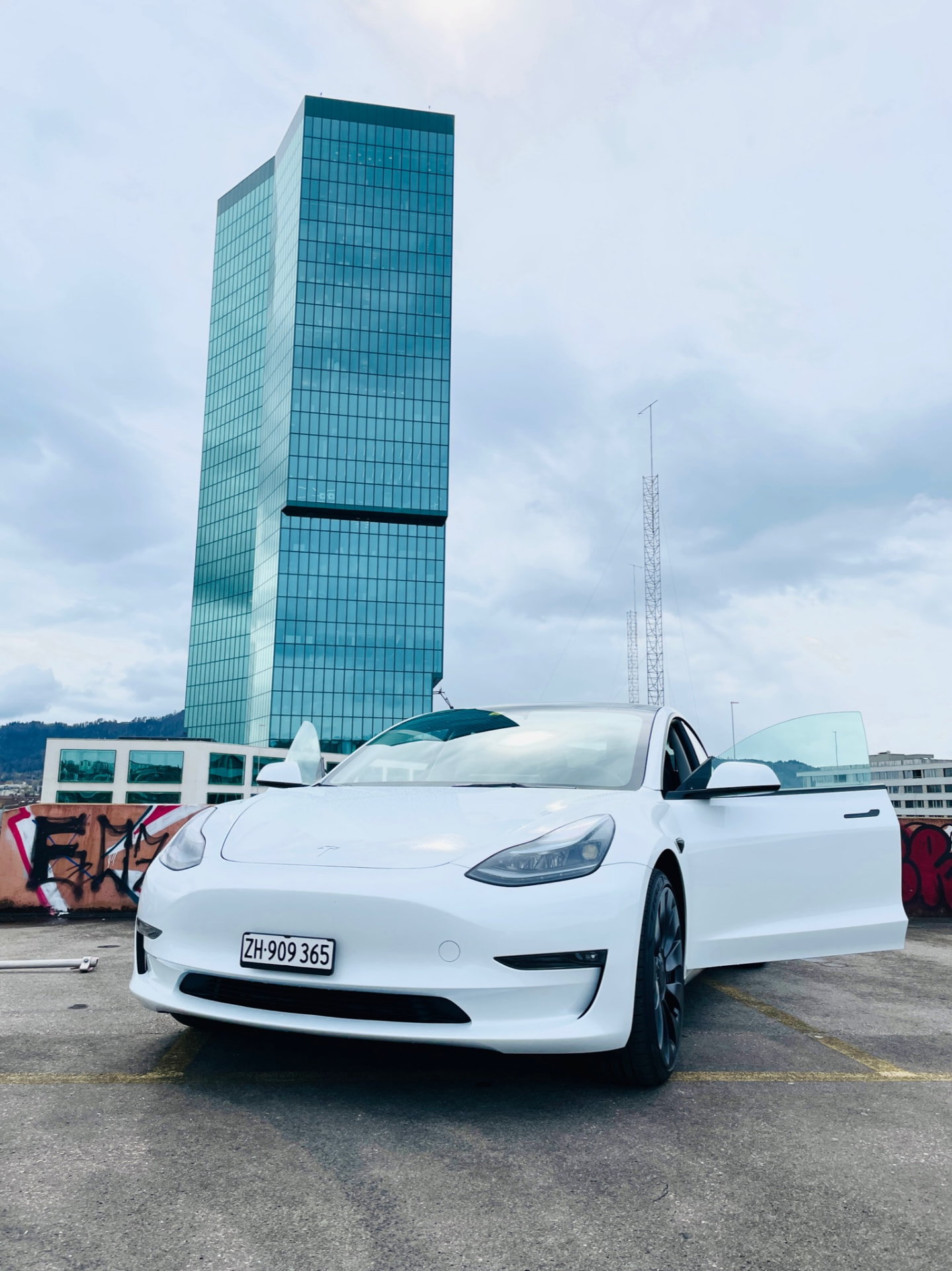Weisser Tesla Model 3 Performance mit offener Tür auf einem Parkdeck